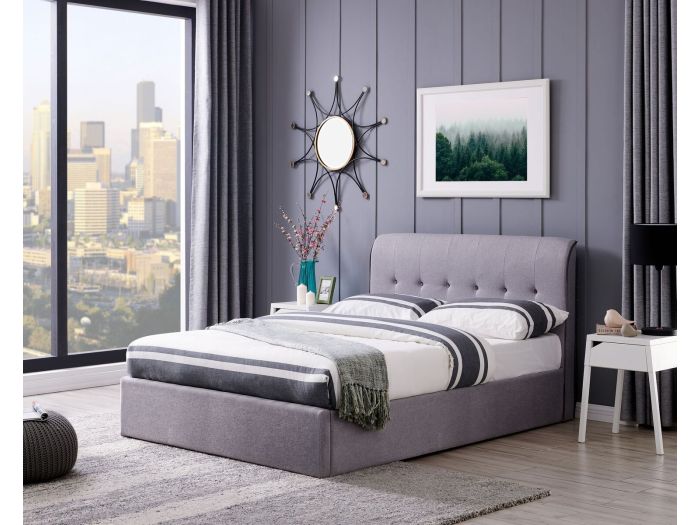 A contemporary, minimalistic grey linen ottoman bed frame. It has a curved headboard with buttons and piping to the edges.